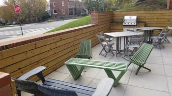 A patio with a table and chairs and a grill